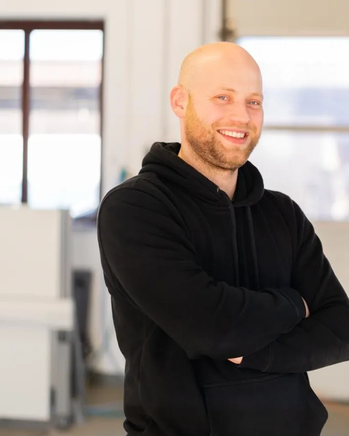 Lutz Rademacher, Geschäftsführer des Saunastudio Münsterland, mit verschränkten Armen in der Werkstatt, freundlich in die Kamera blickend.